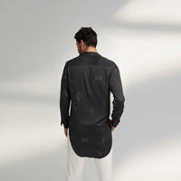 Back view of the longline black and grey tonal print shirt with white trousers
