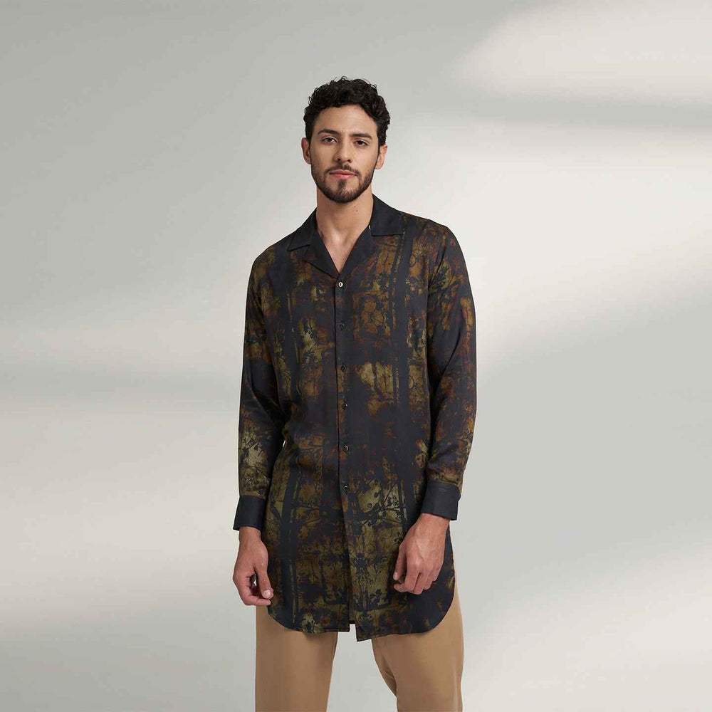 Angled front view of the longline black and olive printed shirt with a notch collar, styled with khaki trousers