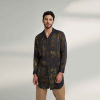 Angled front view of the longline black and olive printed shirt with a notch collar, styled with khaki trousers