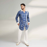 Front view of the longline blue floral print shirt with white contrast trim and white trousers