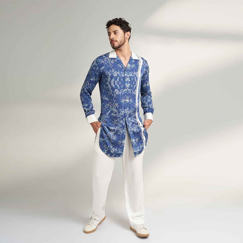 Front view of the longline blue floral print shirt with white contrast trim and white trousers