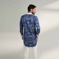 Back view of the longline blue floral print shirt with white trousers