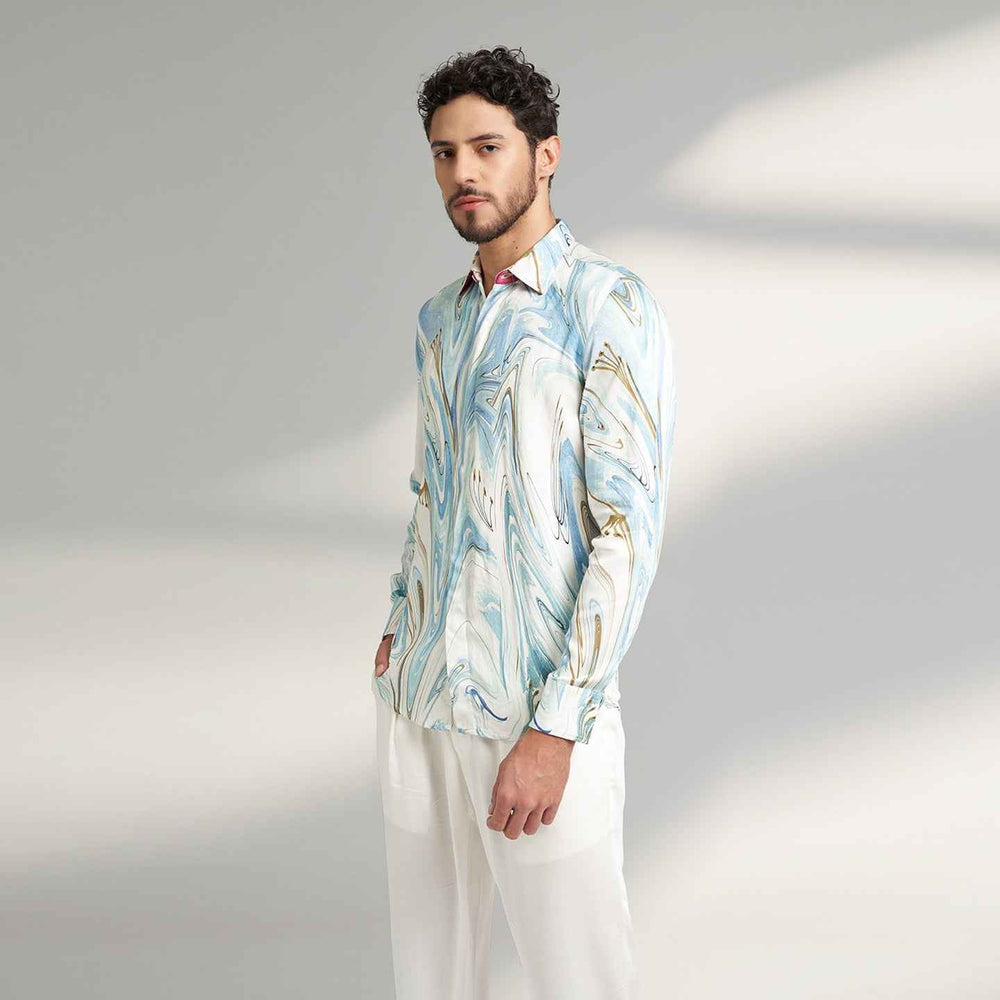 Angled front view of the blue and white marbled print shirt with white trousers
