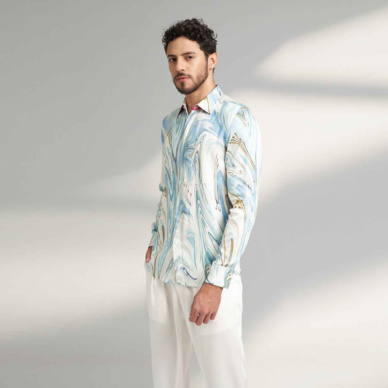 Angled front view of the blue and white marbled print shirt with white trousers