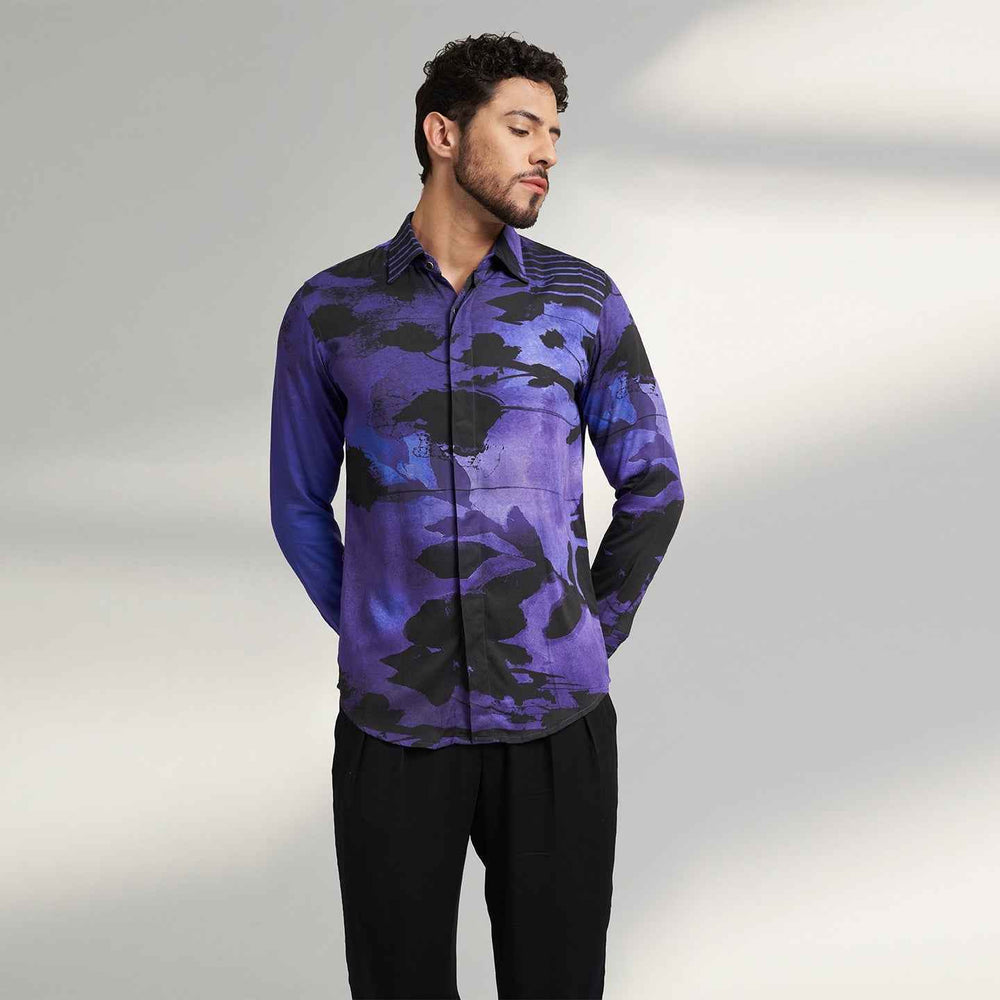 Angled front view of the purple and black abstract floral print shirt styled with black trousers