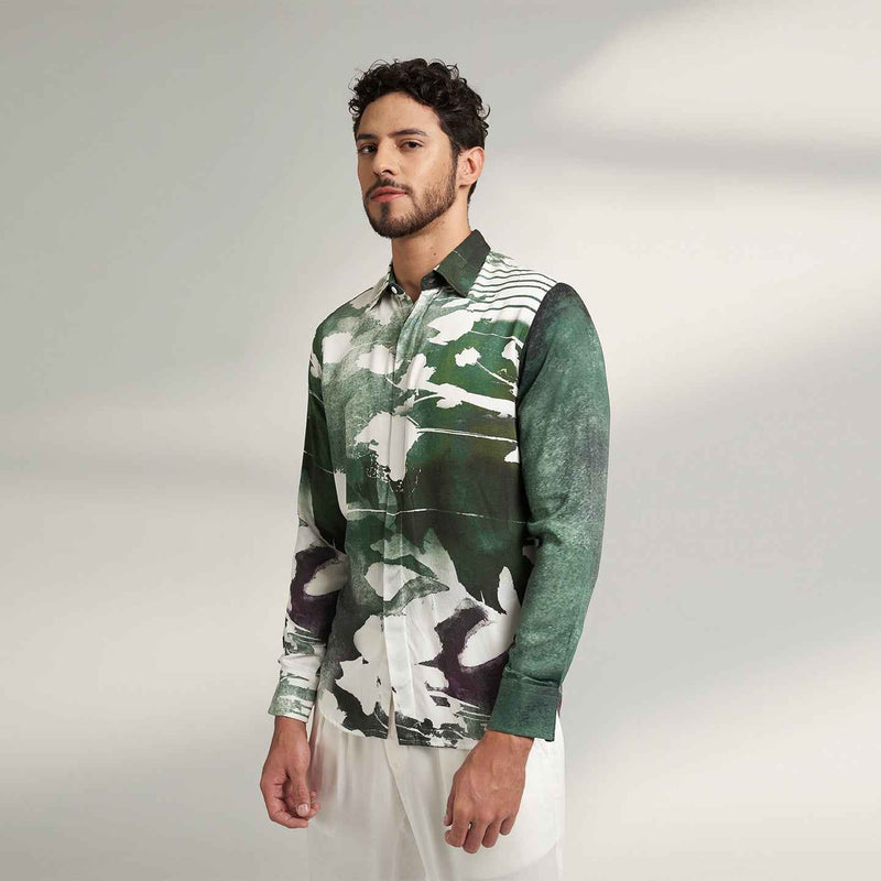 Angled front view of the sea green and white abstract print shirt styled with white trousers