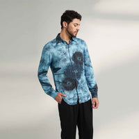 Angled front view of the blue tie-dye print shirt styled with black trousers