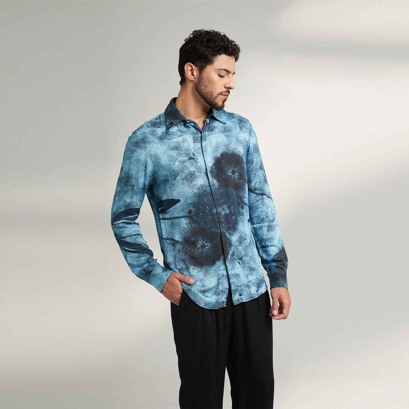 Angled front view of the blue tie-dye print shirt styled with black trousers