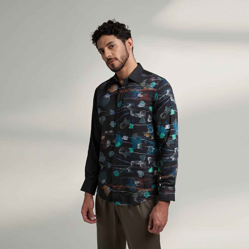 Angled front view of the black floral print shirt styled with olive trousers