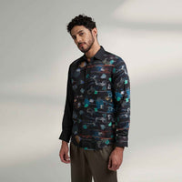 Angled front view of the black floral print shirt styled with olive trousers