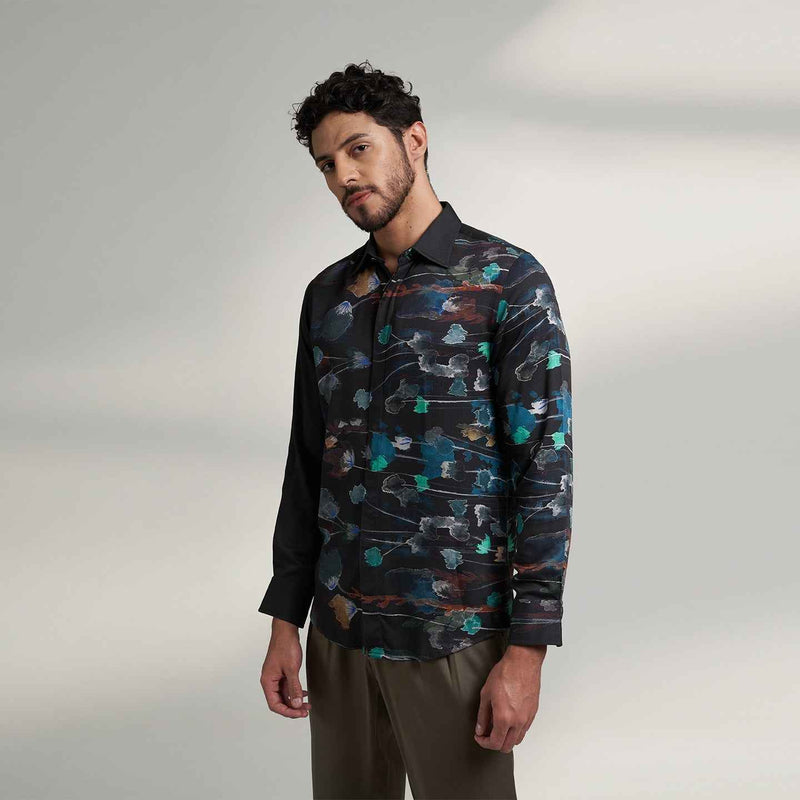 Angled front view of the black floral print shirt styled with olive trousers