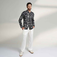 Front view of the black and white leafy print shirt and white trousers