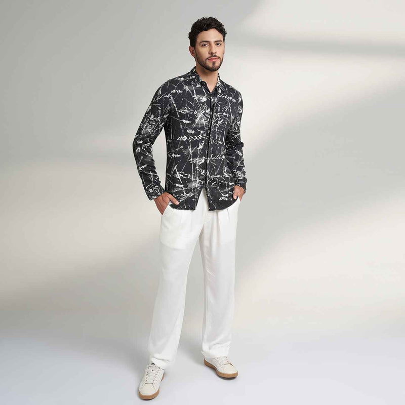 Front view of the black and white leafy print shirt and white trousers