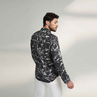 Back view of the black and white leafy print shirt with white trousers