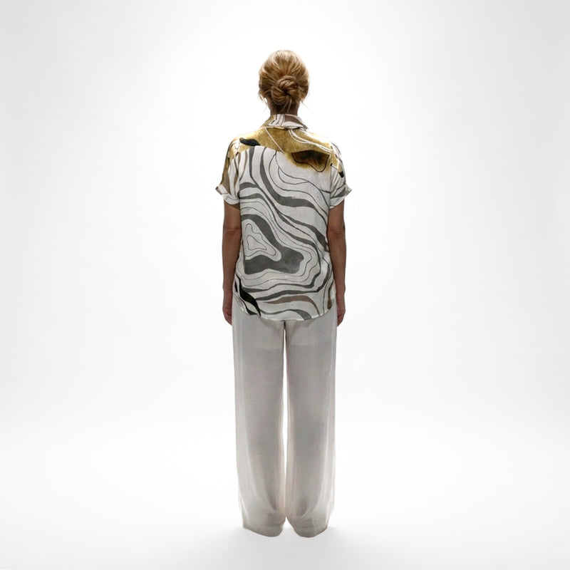 Back view of the abstract print shirt and white wide-leg trousers