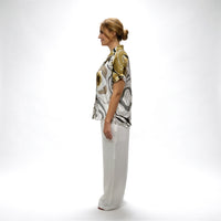Side profile view of the abstract print shirt and white wide-leg trousers