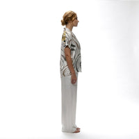 Side view of the abstract brown and gold print shirt with white wide-leg trousers
