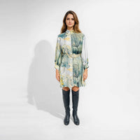 Front view of the multicolor botanical print short dress, belted at the waist, styled with knee-high black boots